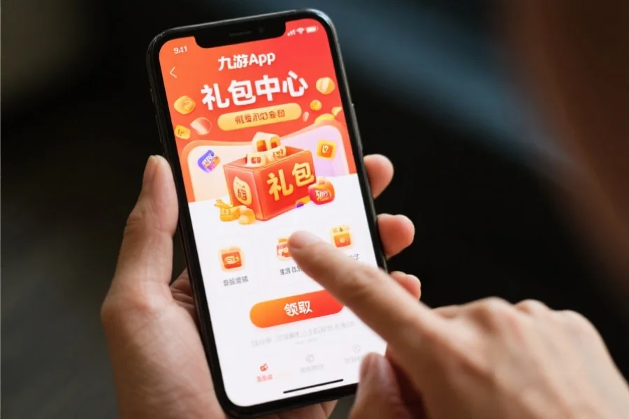 手机屏幕上显示九游App礼包中心，用户正在点击领取按钮，画面突出礼包内容和领取流程